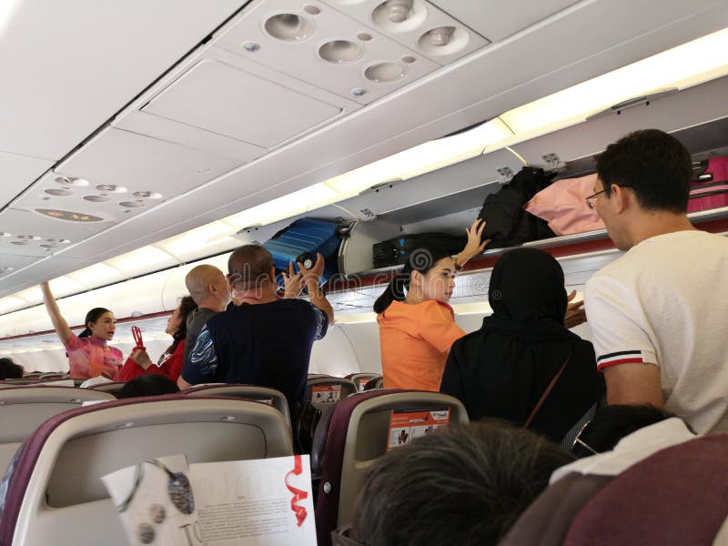 CHIANG RAI, THAILAND - MARCH 29 : unidentified flight attendant helping asian people place luggage in overhead compartment on stock images CHIANG RAI, THAILAND - MARCH 29 : unidentified flight attendant helping asian people place luggage in overhead compartment on stock images
