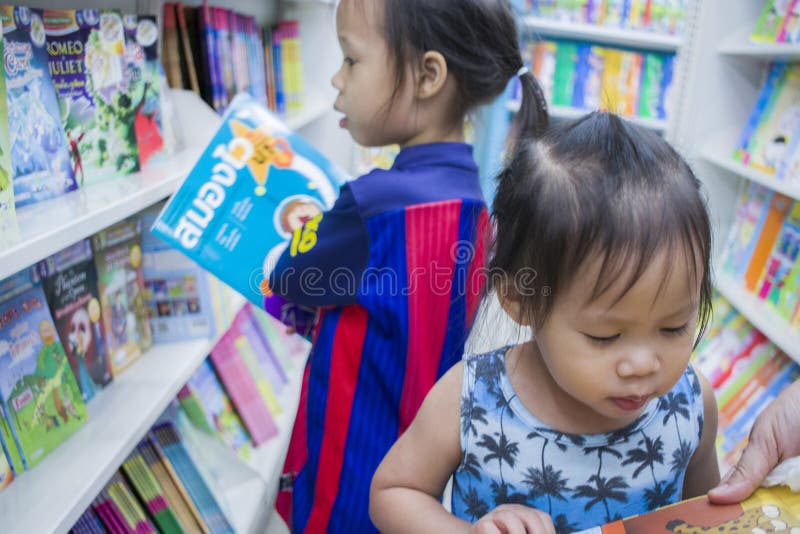 CHIANGMAI,THAILAND-MAY 3,2019 : Little Child explores the bookshelves with mom in book store royalty free stock photo CHIANGMAI,THAILAND-MAY 3,2019 : Little Child explores the bookshelves with mom in book store royalty free stock photo