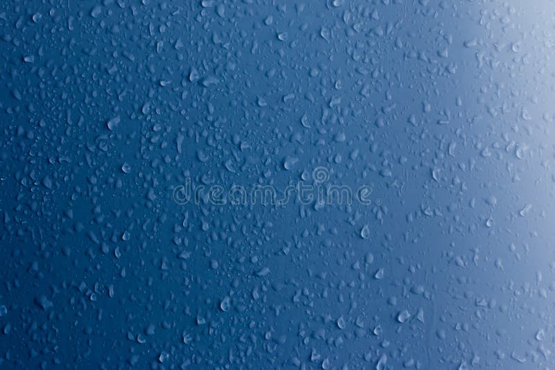Chiare gocce di acqua su una superficie blu sottragga la priorit? bassa immagini stock Chiare gocce di acqua su una superficie blu sottragga la priorit? bassa immagini stock