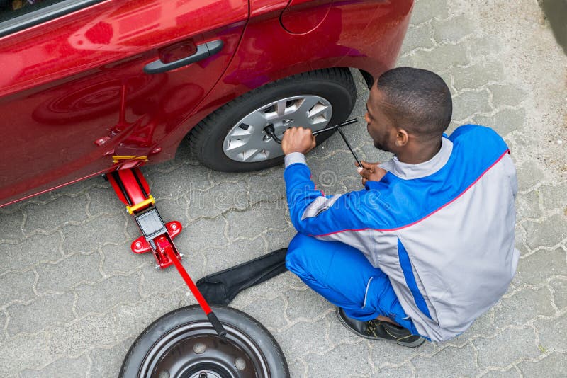 Meccanico che cambia una gomma con una chiave inglese fotografia stock libera da diritti