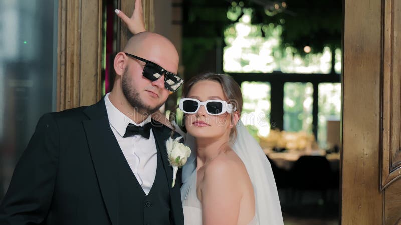 Chic Bride and Groom Wearing Sunglasses Indoor, A stylish bride and groom wearing sunglasses share a playful moment