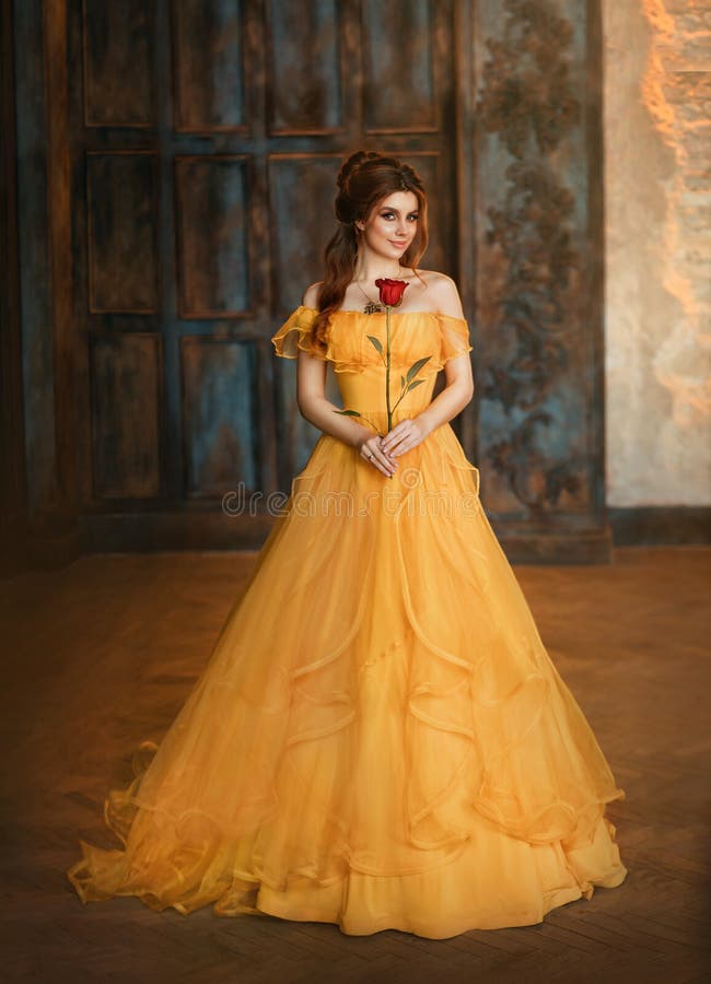 Chica belleza fantasía princesa en amarillo largo histórico vestido de seda medieval sosteniendo la flor rosa roja en sus manos