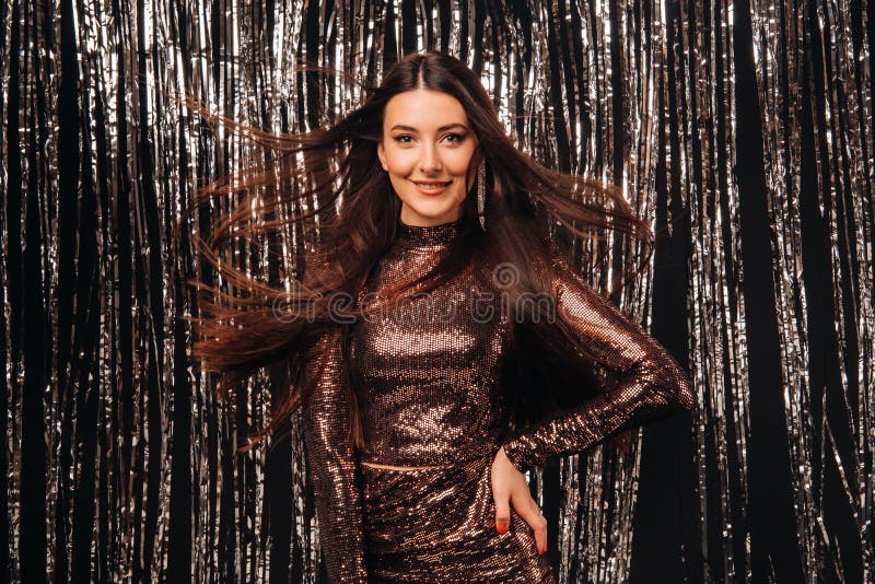 Chica con un vestido brillante con un fondo plateado llueve con el pelo en desarrollo.