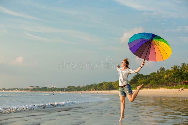 Chica joven alegre con el paraguas del arco iris que tiene imagenes de archivo Chica joven alegre con el paraguas del arco iris que tiene imagenes de archivo