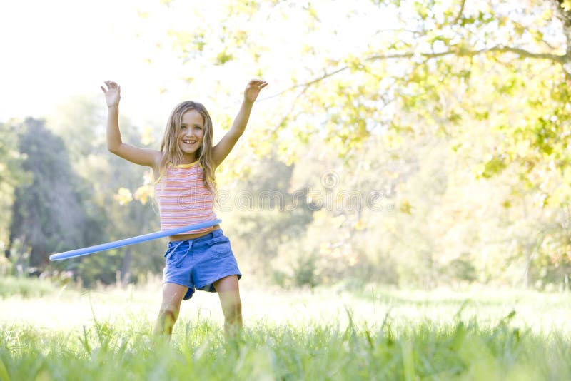 Chica joven con el aro del hula al aire libre que sonríe foto de archivo Chica joven con el aro del hula al aire libre que sonríe foto de archivo