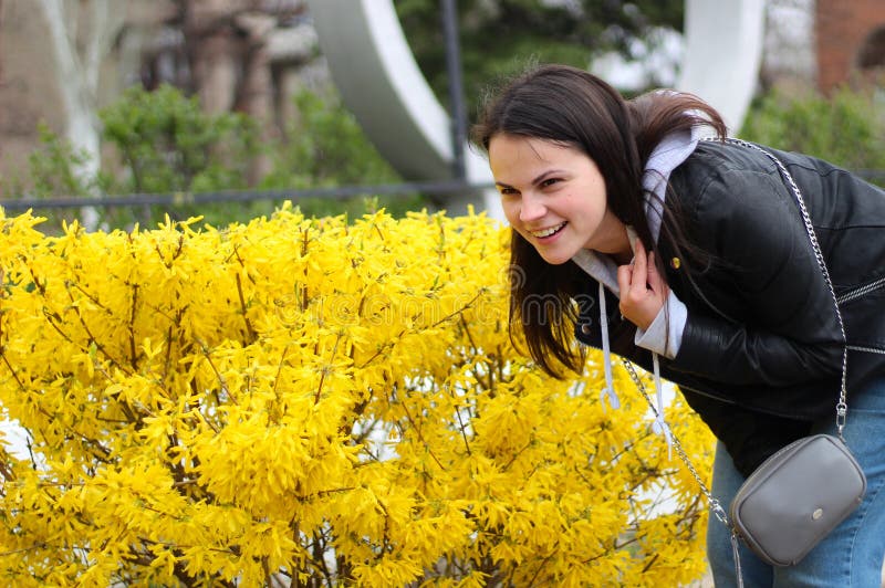 chica joven con el pelo largo en una chaqueta de cuero que sonríe contra la perspectiva de las flores amarillas del arbusto imágenes de archivo libres de regalías chica joven con el pelo largo en una chaqueta de cuero que sonríe contra la perspectiva de las flores amarillas del arbusto imágenes de archivo libres de regalías