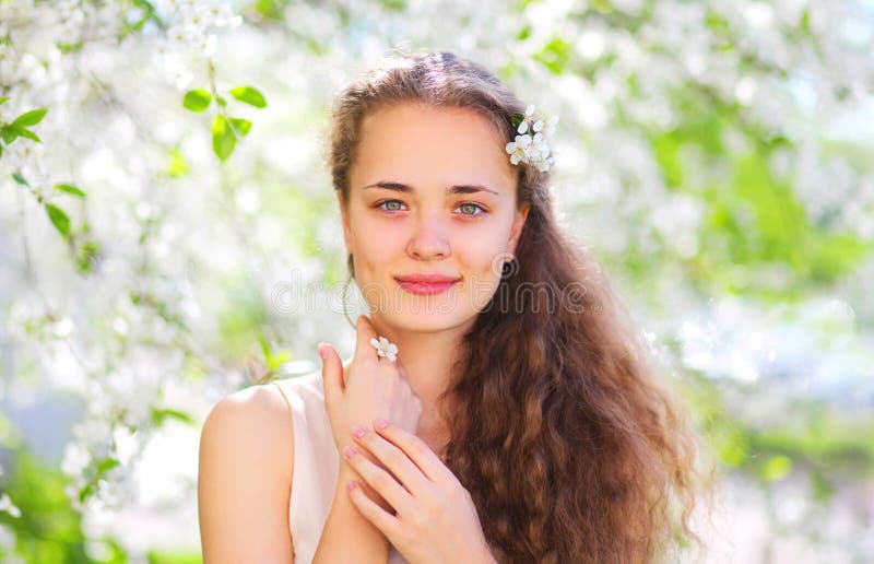 Chica joven hermosa de la primavera con el pelo rizado en jardín floreciente fotografía de archivo libre de regalías Chica joven hermosa de la primavera con el pelo rizado en jardín floreciente fotografía de archivo libre de regalías