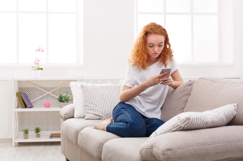 Chica joven pensativa que manda un SMS en smartphone fotos de archivo libres de regalías Chica joven pensativa que manda un SMS en smartphone fotos de archivo libres de regalías
