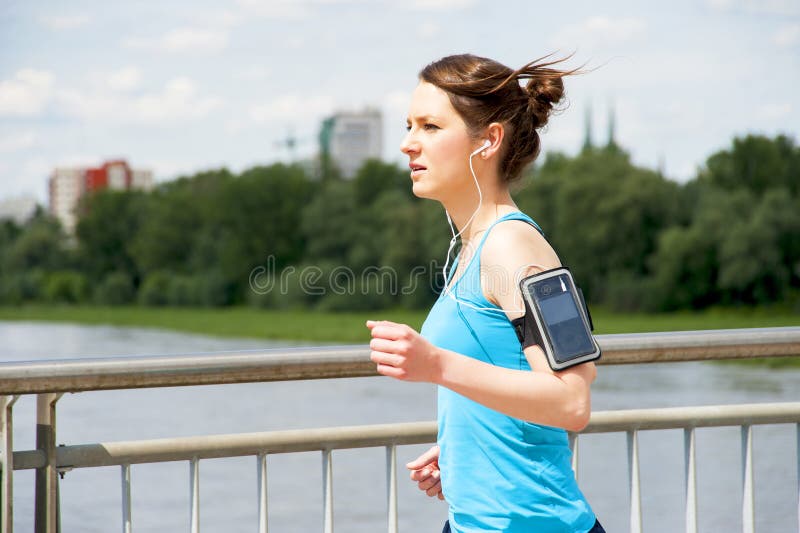 Chica joven que corre en la ciudad, sobre el río por el puente imagen de archivo Chica joven que corre en la ciudad, sobre el río por el puente imagen de archivo