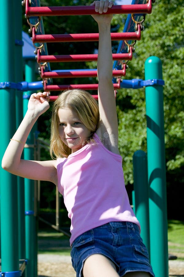 Chica joven que juega en barras de mono en el parque