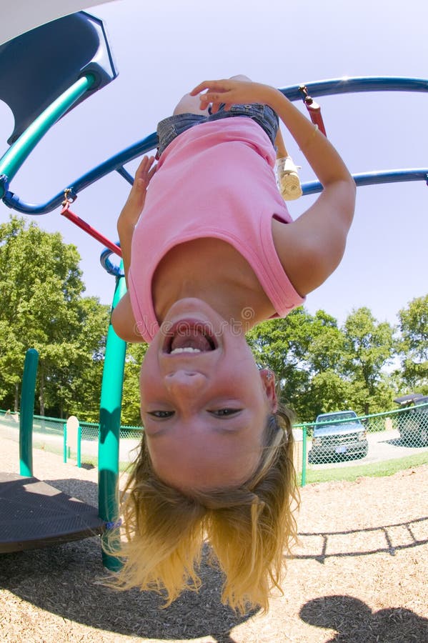 Chica joven que juega en barras de mono en el parque