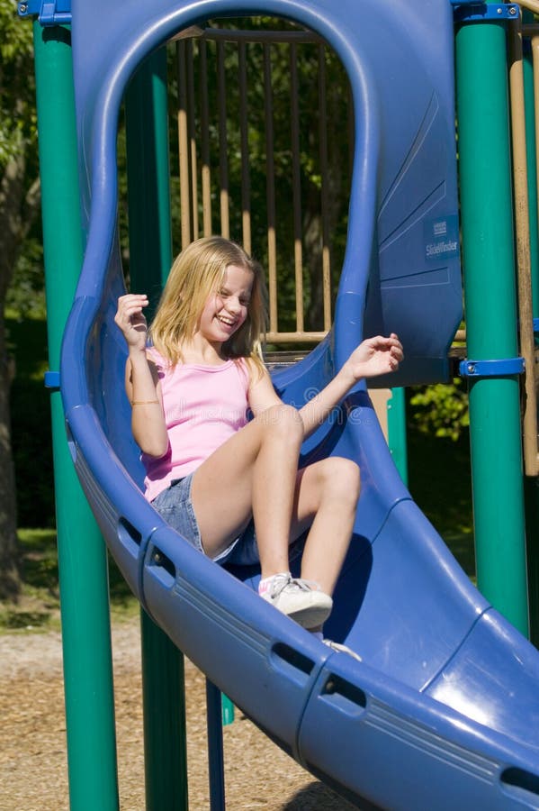 Chica joven que juega en una diapositiva en el parque