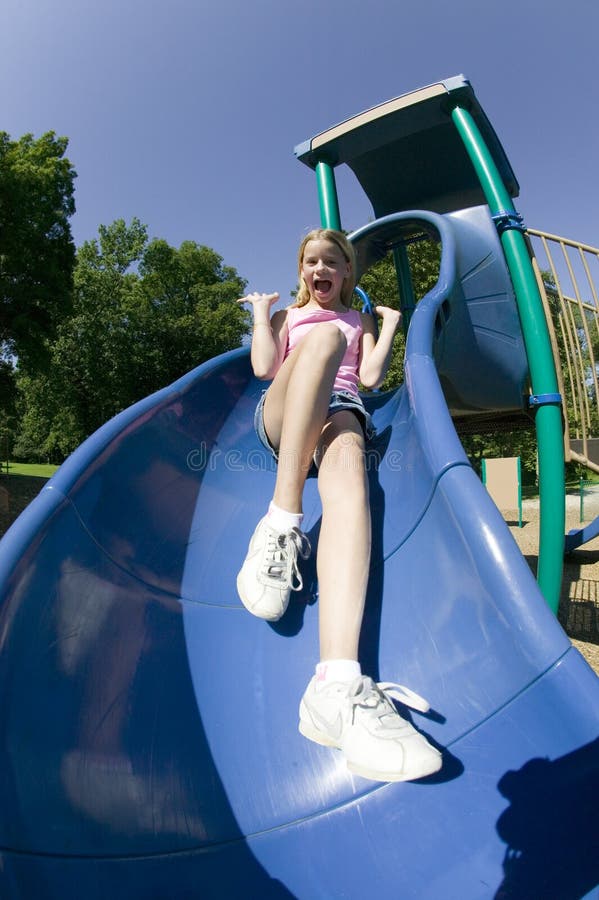 Chica joven que juega en una diapositiva en el parque