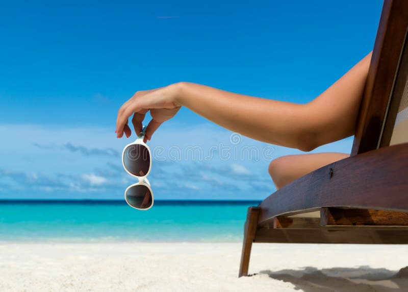 Chica joven que miente en un ocioso de la playa con los vidrios a disposición foto de archivo Chica joven que miente en un ocioso de la playa con los vidrios a disposición foto de archivo