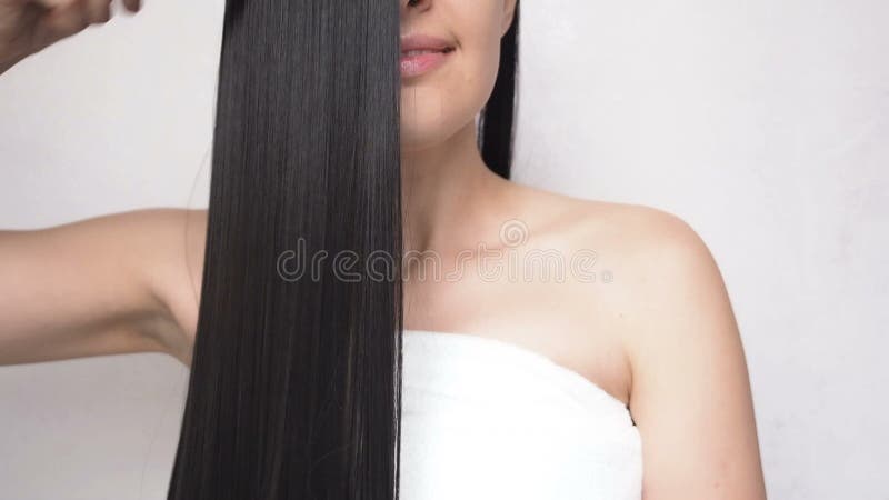 Chica joven que peina el pelo liso largo después de hacer una ducha