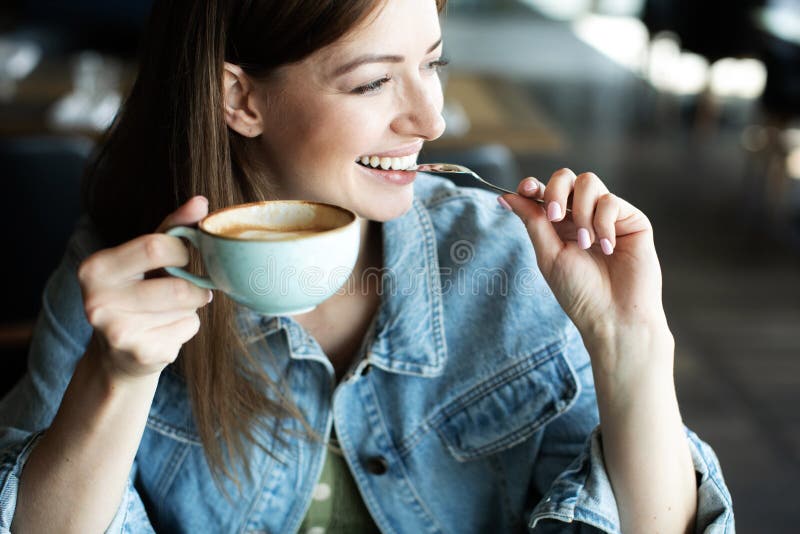 Chica joven que sonríe y que bebe el café delicioso imagen de archivo libre de regalías