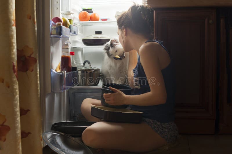 Young girl and her fluffy cat eating at night. Young girl and her fluffy cat eating at night.