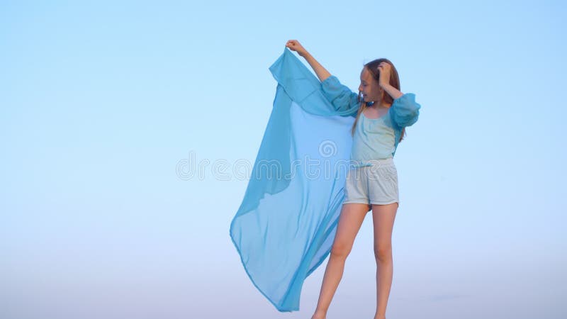 Chica relajada con una túnica azul transparente sobre el viento parada en el desierto en el paisaje del cielo. niña hermosa disfru metrajes