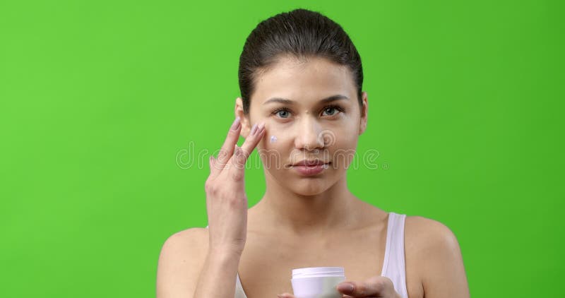 Chica sensacional usando crema cosmética para la cara hidratante