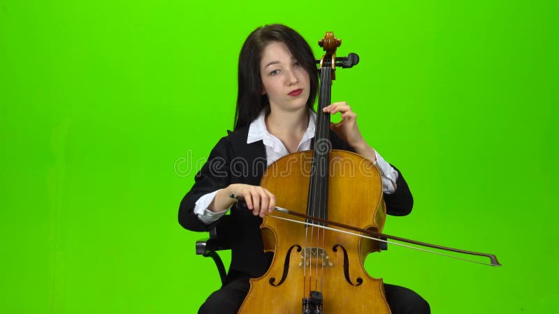 Chica sentada y toca el violonchelo Pantalla verde