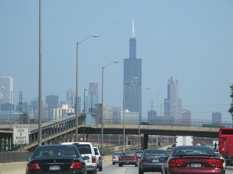 CHICAGO, ILLINOIS, UNITED STATES - JULY 26, 2008: John Hancock building towers upon entering the city from the freeway with moderate traffic on July 26, 2008 in Chicago, United States. CHICAGO, ILLINOIS, UNITED STATES - JULY 26, 2008: John Hancock building towers upon entering the city from the freeway with moderate traffic on July 26, 2008 in Chicago, United States.