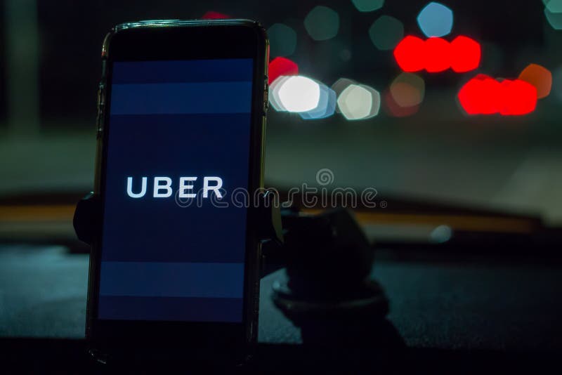 Chicago, IL, los E.E.U.U., Feb-21,2017, Smartphone ató a un soporte del coche en coche con el logotipo de Uber en la noche para e imagen de archivo Chicago, IL, los E.E.U.U., Feb-21,2017, Smartphone ató a un soporte del coche en coche con el logotipo de Uber en la noche para e imagen de archivo