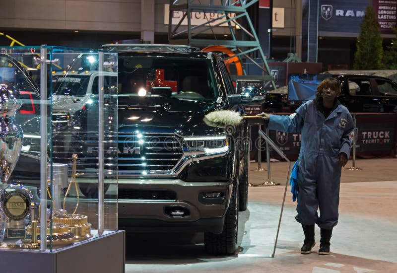 CHICAGO, ILLINOIS - February 8, 2020: Female person dusting a RAM pickup truck displayed at McCormick Place at the annual Chicago Auto Show. CHICAGO, ILLINOIS - February 8, 2020: Female person dusting a RAM pickup truck displayed at McCormick Place at the annual Chicago Auto Show