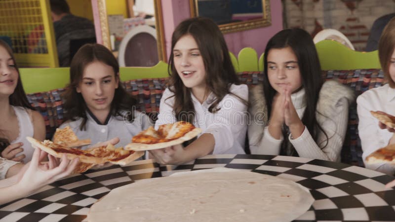 Chicas jóvenes bonitas que comen la pizza y fuving una diversión en café 4K almacen de metraje de vídeo