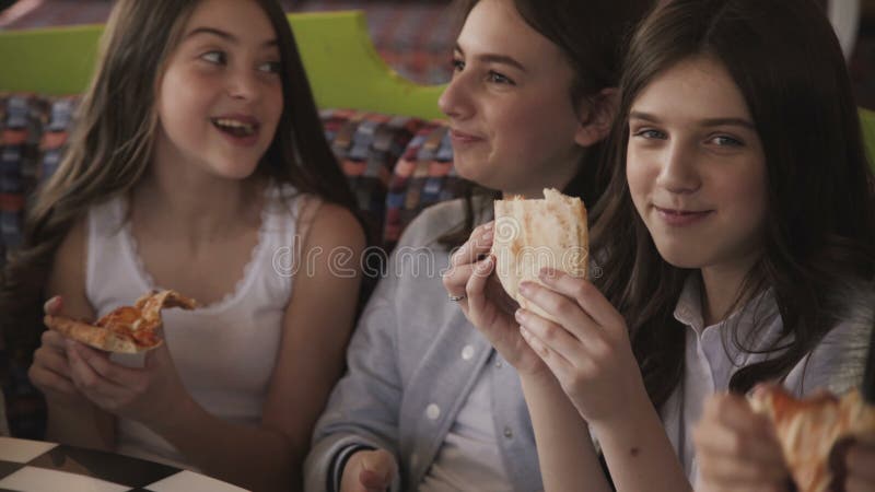 Chicas jóvenes bonitas que comen la pizza y fuving una diversión en café 4K almacen de video