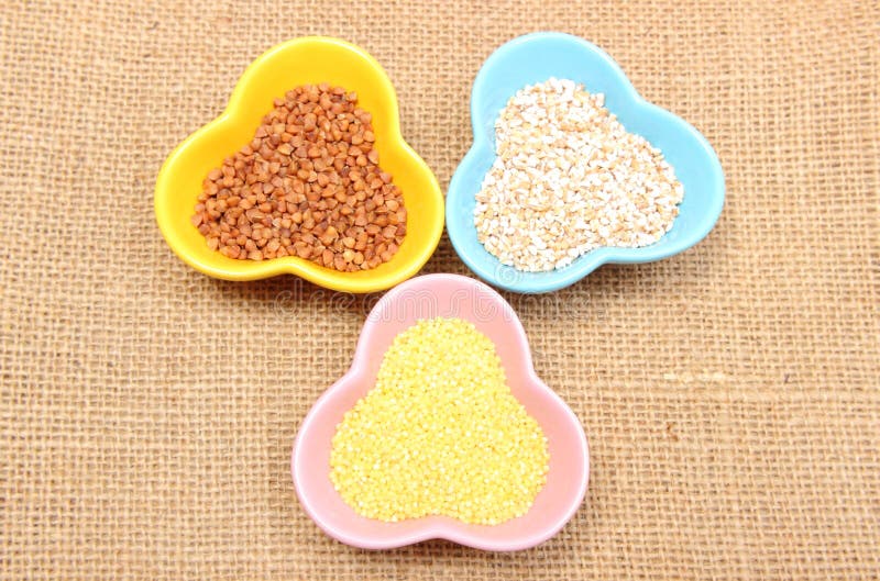 Chicchi del grano saraceno, dell'orzo e del miglio in ciotola variopinta fotografia stock libera da diritti Chicchi del grano saraceno, dell'orzo e del miglio in ciotola variopinta fotografia stock libera da diritti