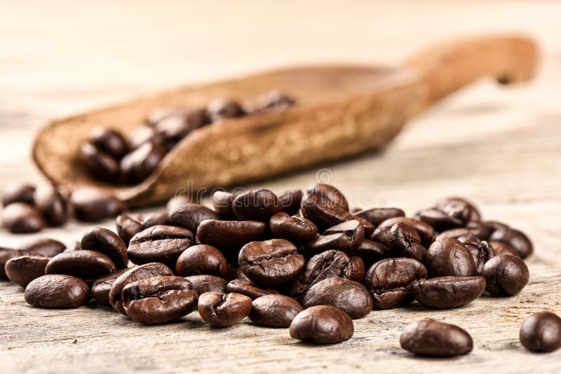 Chicchi di caffè arrostiti con il vecchio mestolo di legno fotografia stock Chicchi di caffè arrostiti con il vecchio mestolo di legno fotografia stock