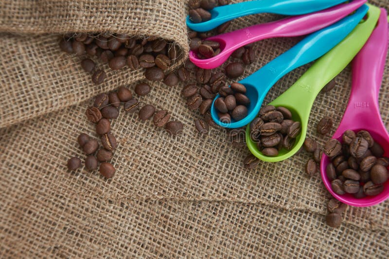 Chicchi di caffè arrostiti, di dosatore della dose sul sacco della iuta immagine stock Chicchi di caffè arrostiti, di dosatore della dose sul sacco della iuta immagine stock
