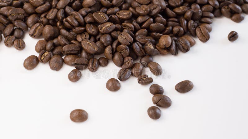 Chicchi di caffè arrostiti sparsi su un fondo bianco fotografia stock Chicchi di caffè arrostiti sparsi su un fondo bianco fotografia stock