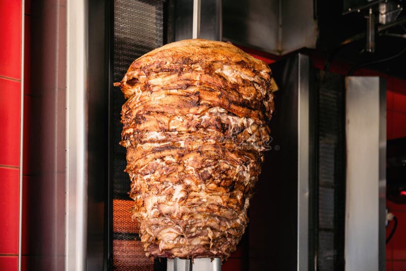 A close-up shot of delicious Doner kebab meat on a rotating vertical spit. A close-up shot of delicious Doner kebab meat on a rotating vertical spit.