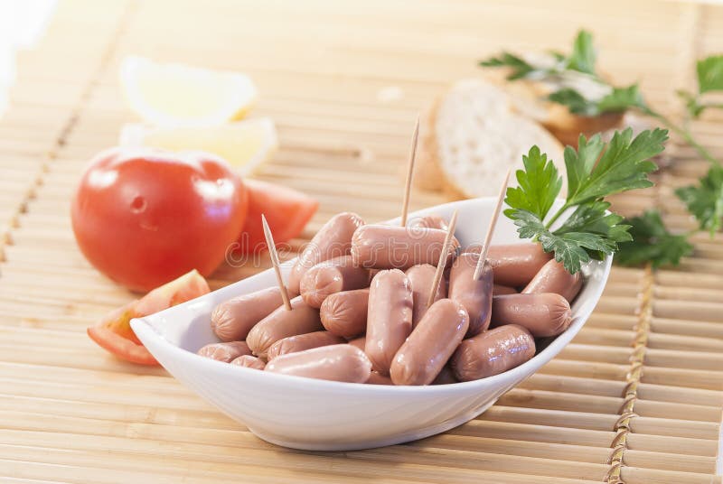 Chicken & Beef cocktail sausage with cherry tomato radish and lemon with green herb with toast bread on green red and bamboo backg. Creative food photography for stock photography Chicken & Beef cocktail sausage with cherry tomato radish and lemon with green herb with toast bread on green red and bamboo backg. Creative food photography for stock photography