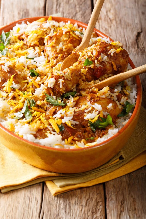 Chicken biryani with spices, lemon and greens close-up in a dish on the table. vertical. Chicken dum biryani stock images, royalty-free photos and pictures