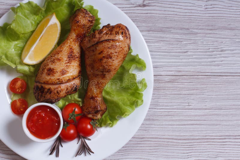 Chicken drumstick with lettuce, tomatoes and ketchup top view