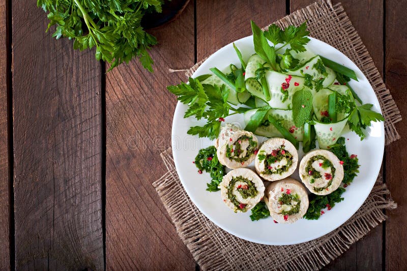 Steamed chicken rolls with greens and fresh vegetable salad on a plate