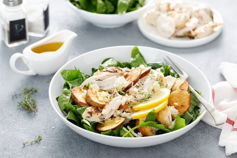 Chicken salad with spinach and crispy potatoes dressed with olive oil, garlic, lemon, onion and thyme