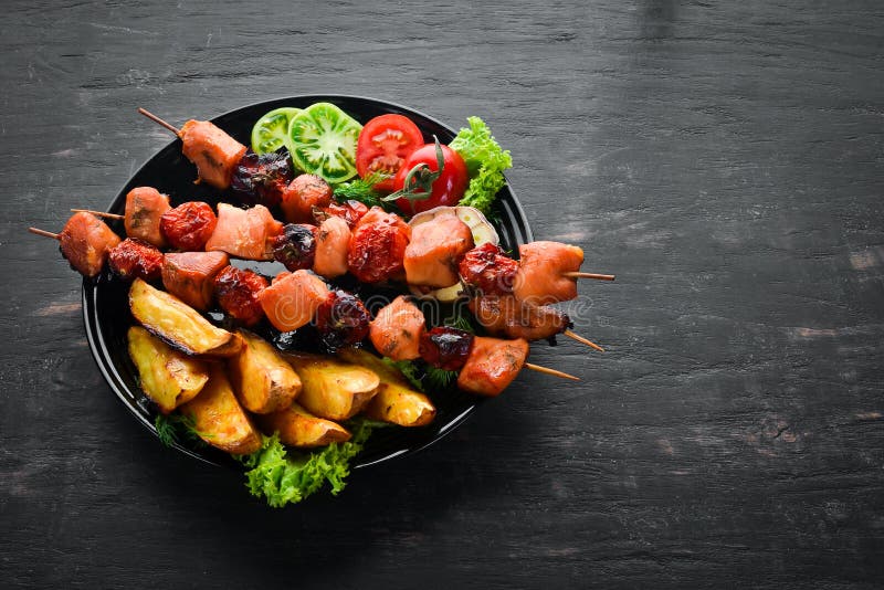 Chicken Shish Kebab with Potatoes and Vegetables on a Black Background ...