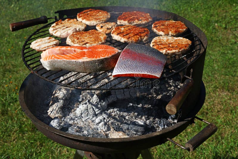 Chicken or turkey burgers and salmon fish on grill