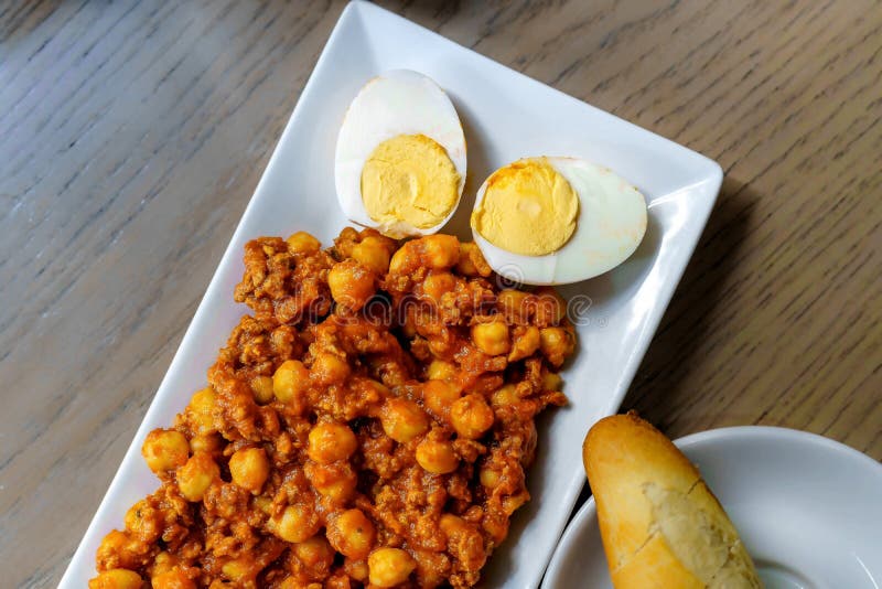 Chickpeas with Tomato, Sausage and Hardboiled Egg. Wooden Table Stock