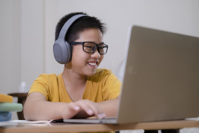 Chico asiático disfruta de autoestudiar con elearning en casa foto de archivo