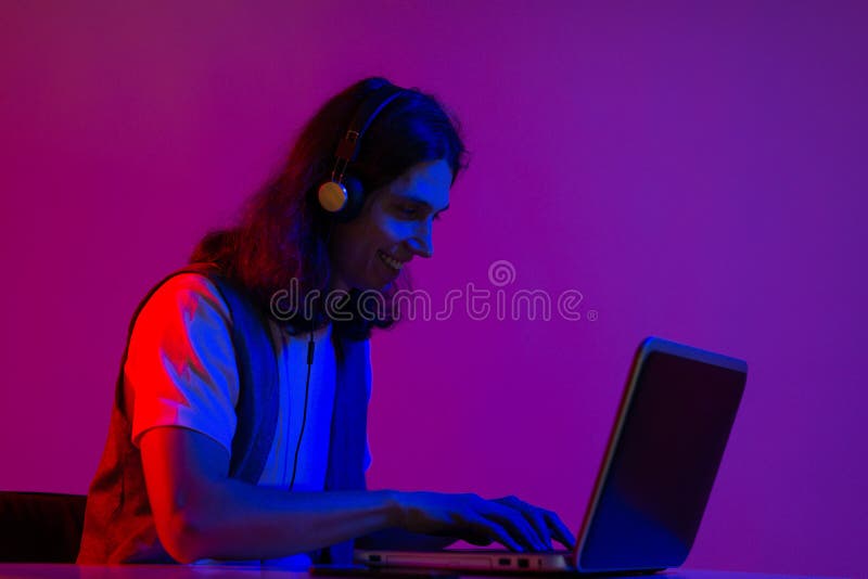 Chico divertido jugador jugando en un portátil. un joven con auriculares fotos de archivo libres de regalías