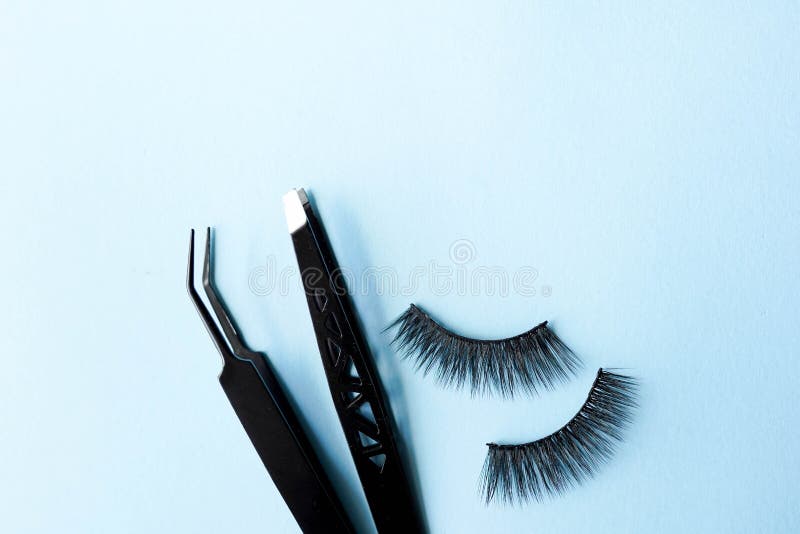 False eye lashes, black tweezers on blue background with copy space, mockup. Beauty concept - Tools for eyelash extension. False eye lashes, black tweezers on blue background with copy space, mockup. Beauty concept - Tools for eyelash extension.
