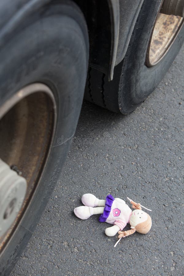 Wheels of a truck and a doll on the asphalt after an accident with a little child. Wheels of a truck and a doll on the asphalt after an accident with a little child