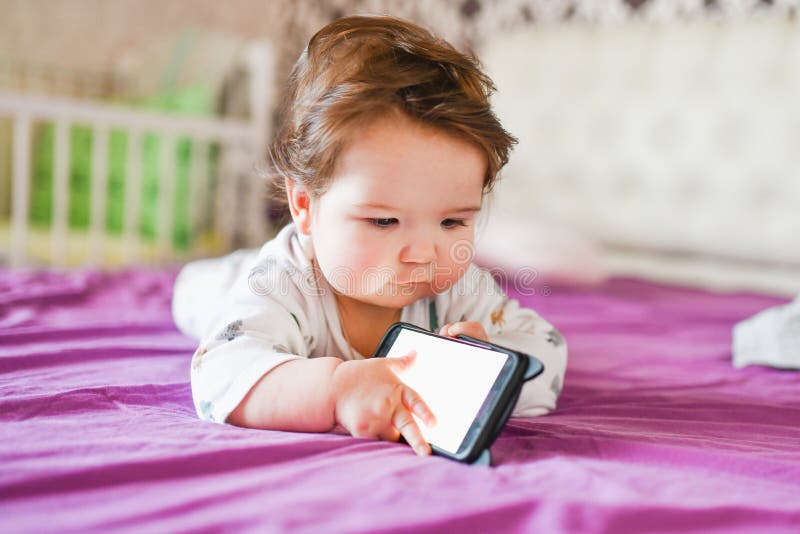 Child addiction to phones. radiation from the phone to the child. A little boy 0-1 years old with a smartphone in his hands looks