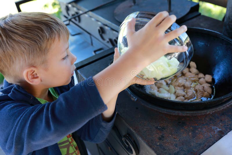 Child adding onions to cauldron royalty free stock photos