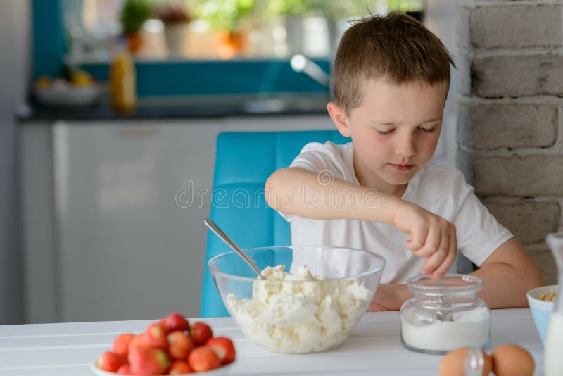 Child adding sugar to cottage cheese in a bowl. royalty free stock images
