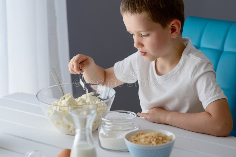 Child adding sugar to cottage cheese in a bowl. royalty free stock photography